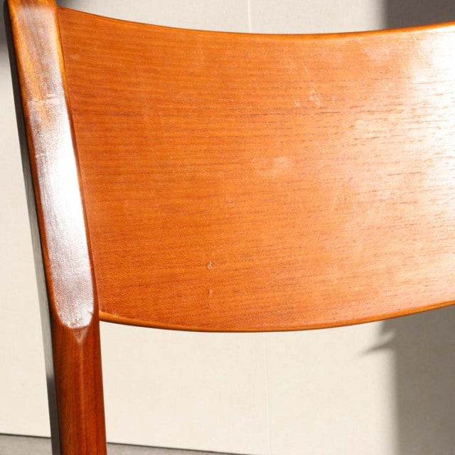 Mid-century British vintage teak dining chair backrest with warm wood grain and smooth finish.