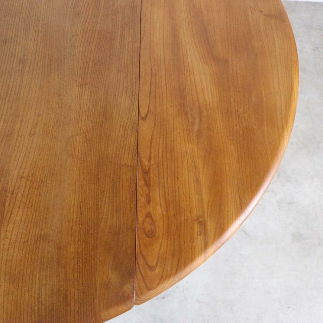 Vintage British mid-century Ercol dining table in warm teak with drop-leaf design and smooth wood grain visible on rounded.