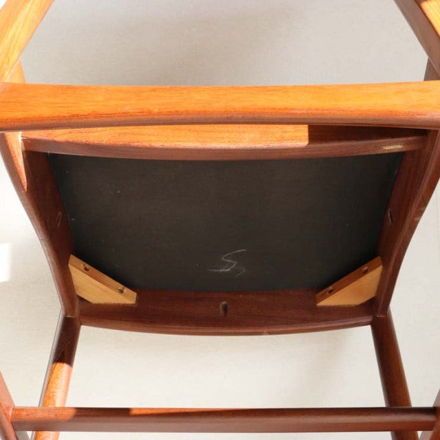 Mid-century British vintage teak dining chair seen from underside, solid wood frame with visible grain and sturdy legs.