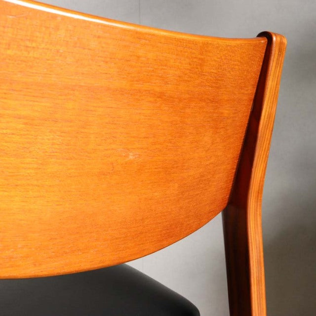 Close-up of vintage teak dining chair backrest with smooth wood grain and mid-century British-Denmark design.