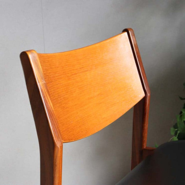Vintage British mid-century teak dining chair with smooth curved backrest and visible wood grain.