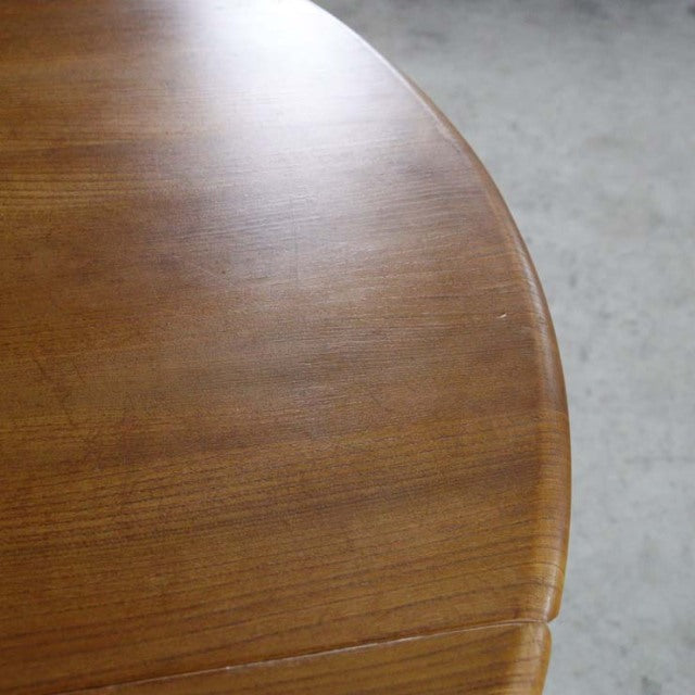 Mid-century British vintage Ercol dining table with smooth teak grain and rounded drop-leaf edge.