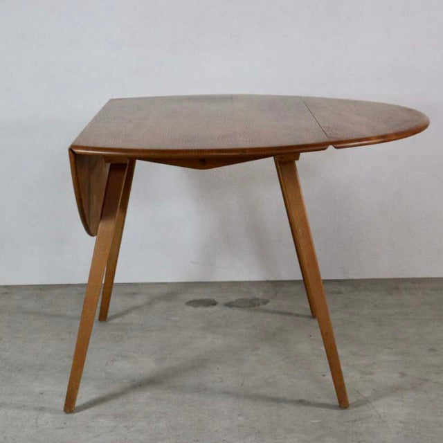 Vintage British mid-century Ercol dining table in teak with drop leaf, tapered legs, and smooth wood grain.