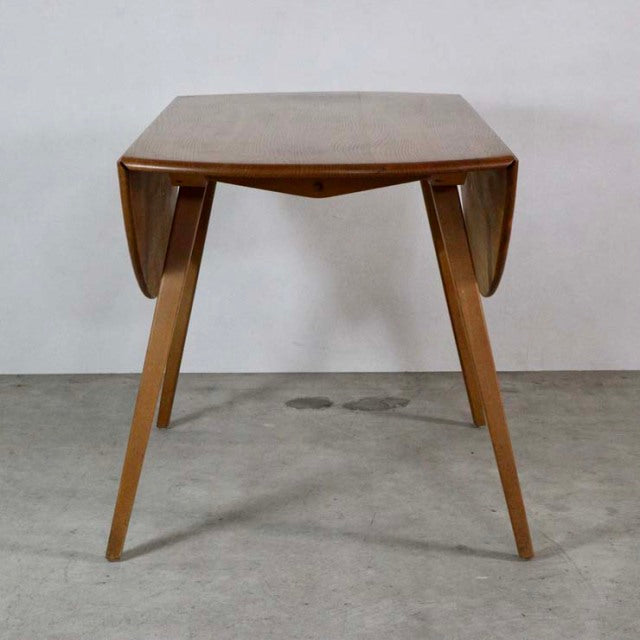 Mid-century British vintage teak dining table by Ercol with angled legs and drop-leaf sides.