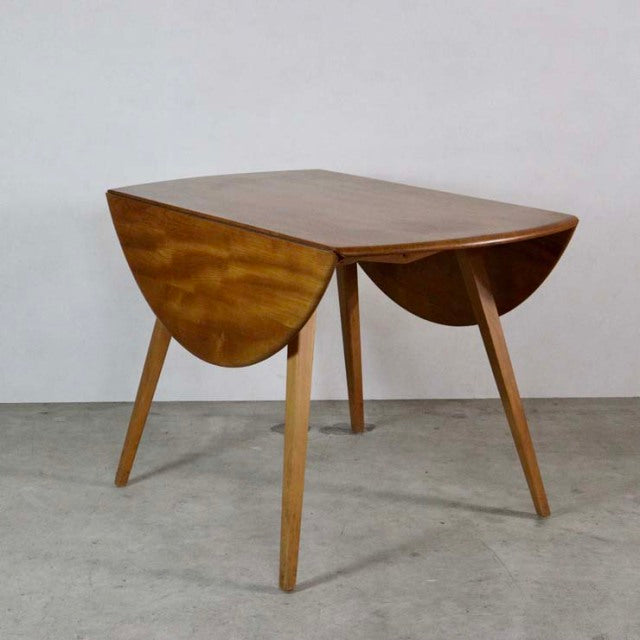 Mid-century British vintage ERCOL dining table in teak with drop-leaf design, rounded edges, and tapered legs showing warm.