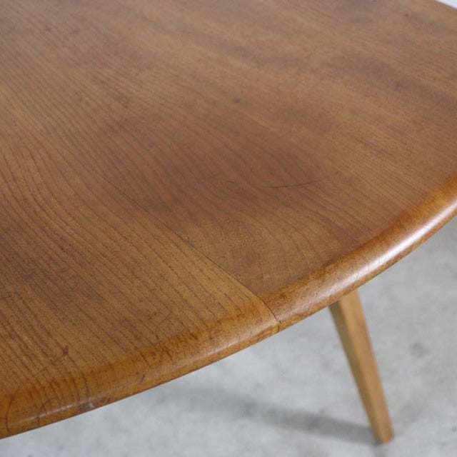 Mid-century British vintage Ercol dining table drop-leaf in warm teak with smooth rounded edges and visible wood grain on.