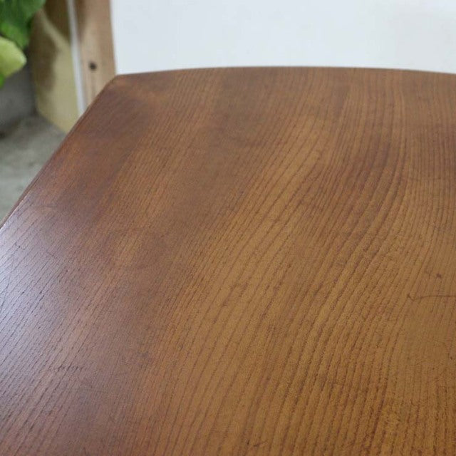 Vintage British mid-century Ercol dining table in warm teak with smooth oval top and visible wood grain.