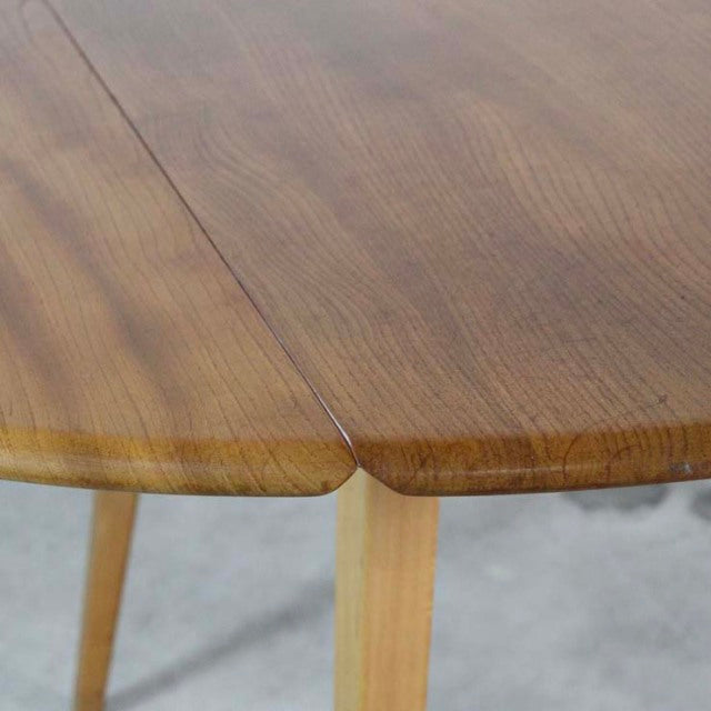 Close-up of vintage British mid-century Ercol teak drop-leaf dining table showing smooth wood grain and rounded edge with.