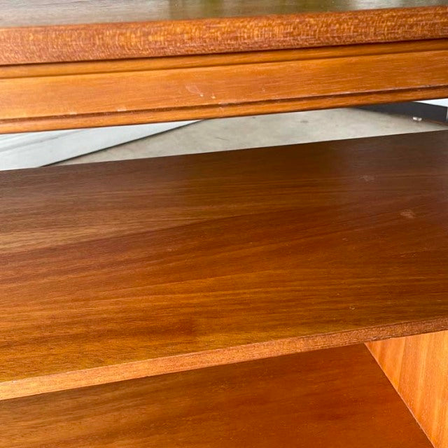 Close-up of mid-century vintage teak wood grain on British-designed TV board with smooth edges and sleek iron legs.