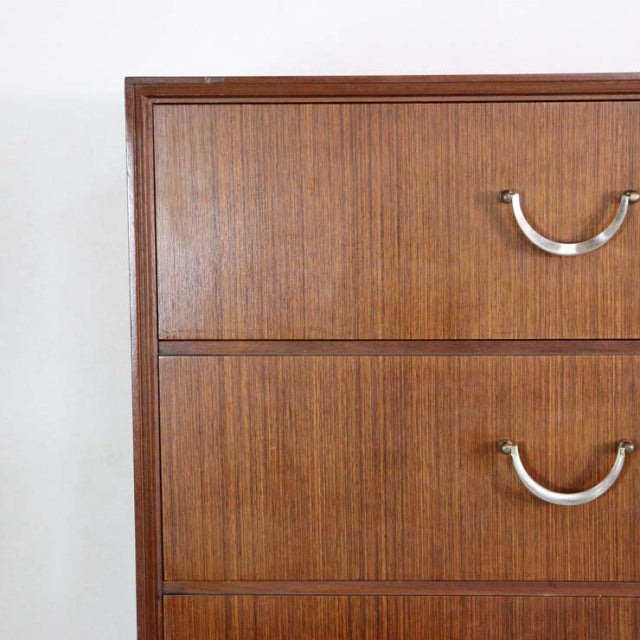 Vintage teak mid-century British chest of drawers with visible wood grain and curved metal handles, clean lines typical of.