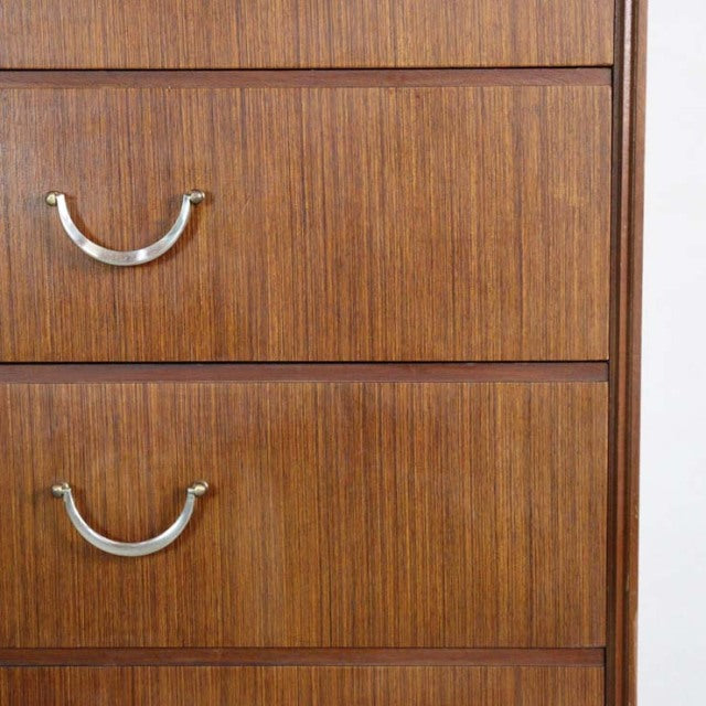 Close-up of vintage British mid-century teak chest drawers with curved metal handles and rich wood grain.