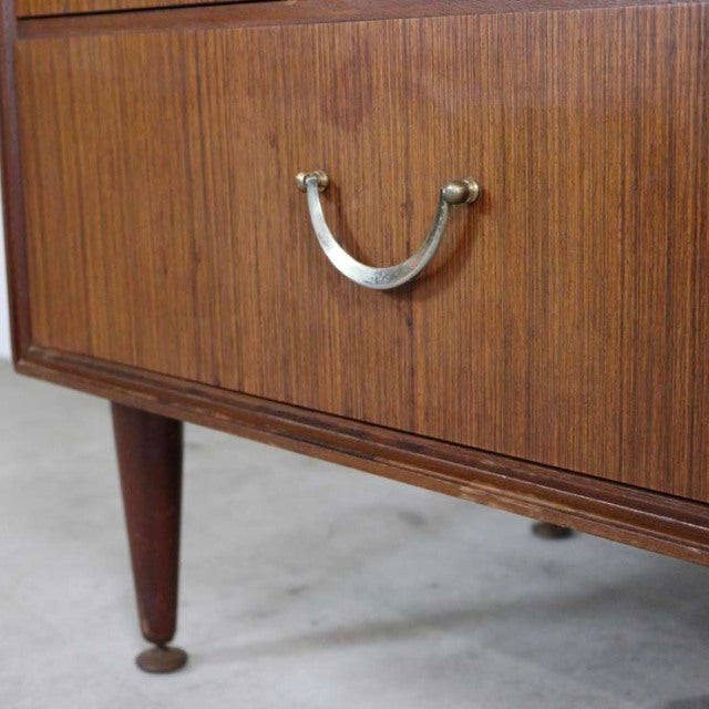 Mid-century vintage teak chest drawer with brass handle and tapered British-style legs showing rich wood grain from Denmark.