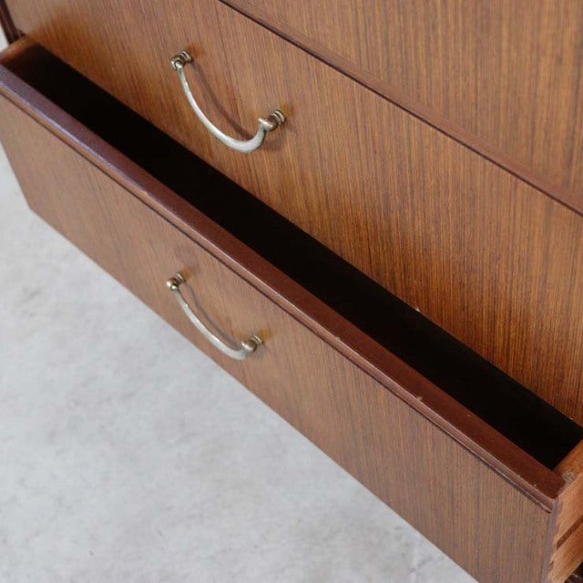 Vintage teak mid-century chest of drawers with brass handles and fine wood grain detailing.