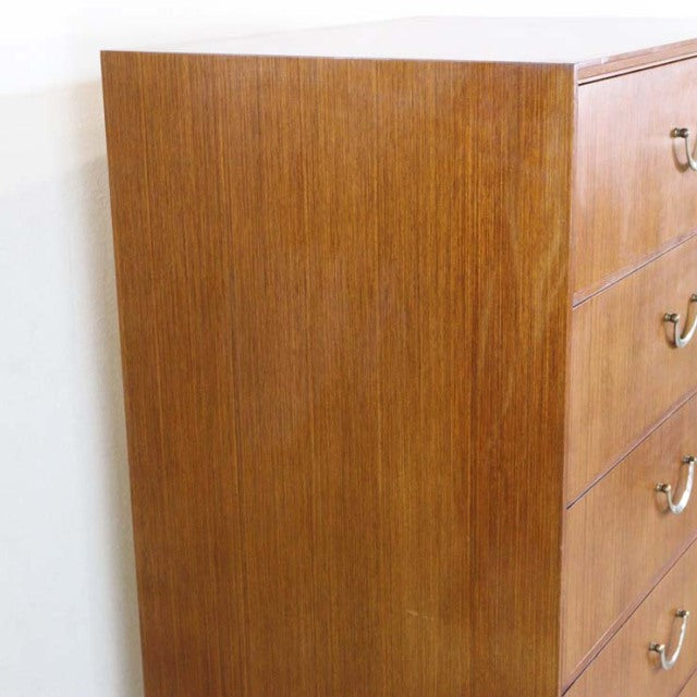 Mid-century British teak vintage six-drawer chest with sleek wood grain and curved brass handles.