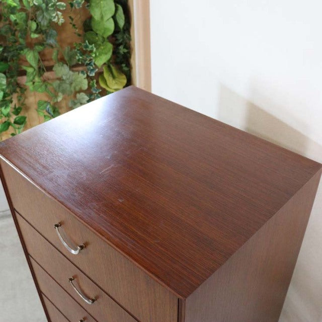 Vintage teak mid-century British chest of drawers with smooth wood grain and metal handles.