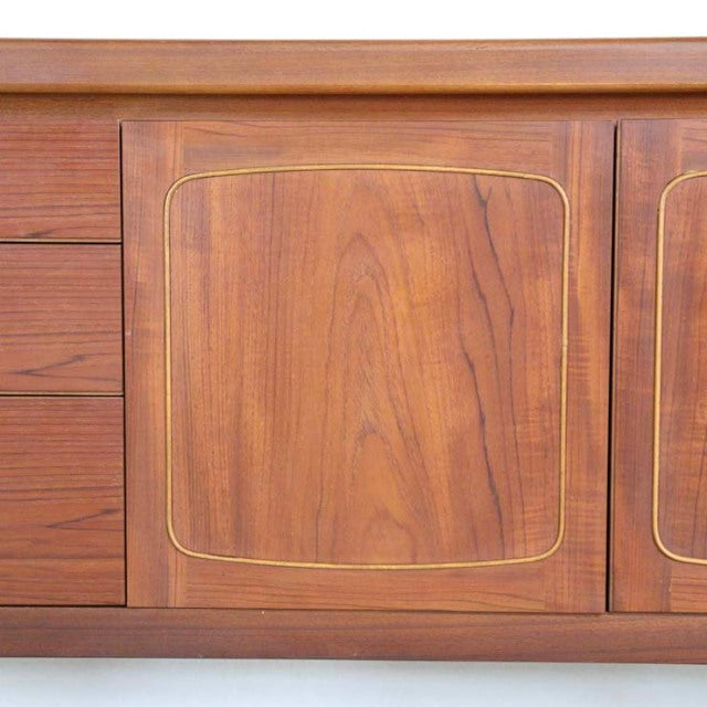 Close-up of vintage British NATHAN teak sideboard door with smooth wood grain and inset rounded square detail in mid-century .