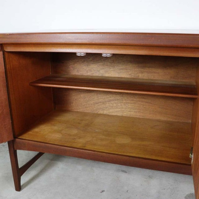 Mid-century British vintage teak sideboard by Nathan with rich wood grain, open door revealing adjustable shelf and slender.
