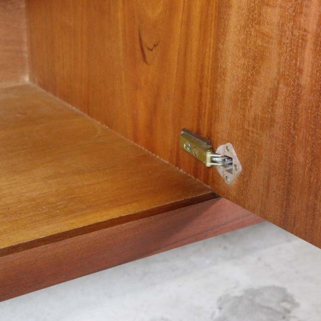 Close-up of vintage teak mid-century sideboard interior showing smooth wood grain and brass hinge detail from British brand.