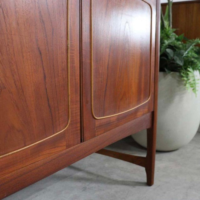 Mid-century British vintage teak sideboard by Nathan with curved doors, visible wood grain, and tapered legs from Denmark.