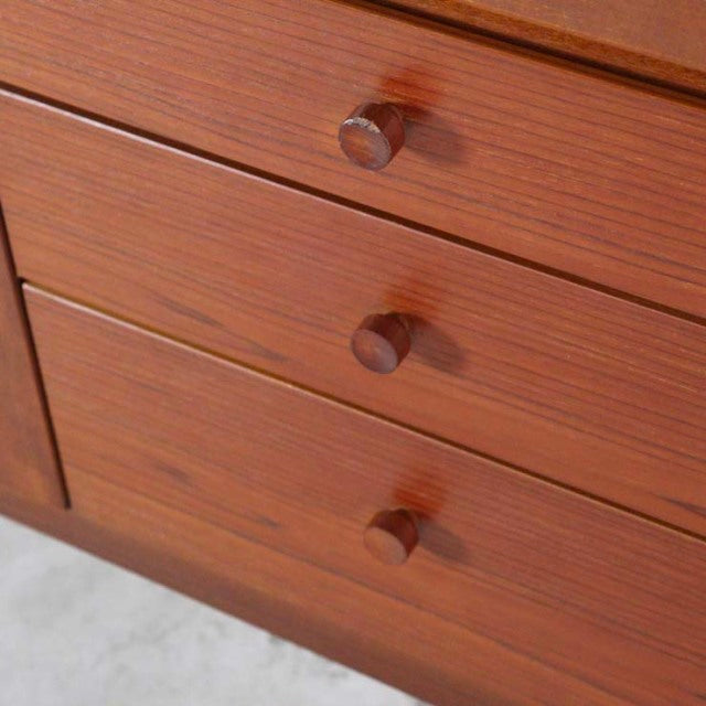 Close-up of vintage British mid-century Nathan teak sideboard drawers with round wooden knobs and warm wood grain texture.