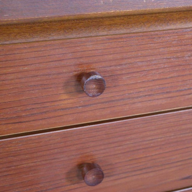 Close-up of vintage teak sideboard drawer front showing rich wood grain and round wooden knobs, mid-century British design.