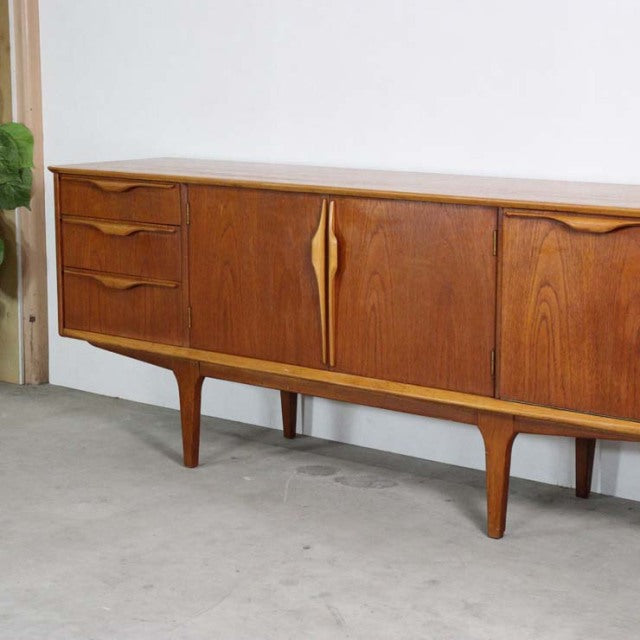 Mid-century British vintage teak sideboard by Jentique with sculpted handles, wood grain, and elegant tapered legs.