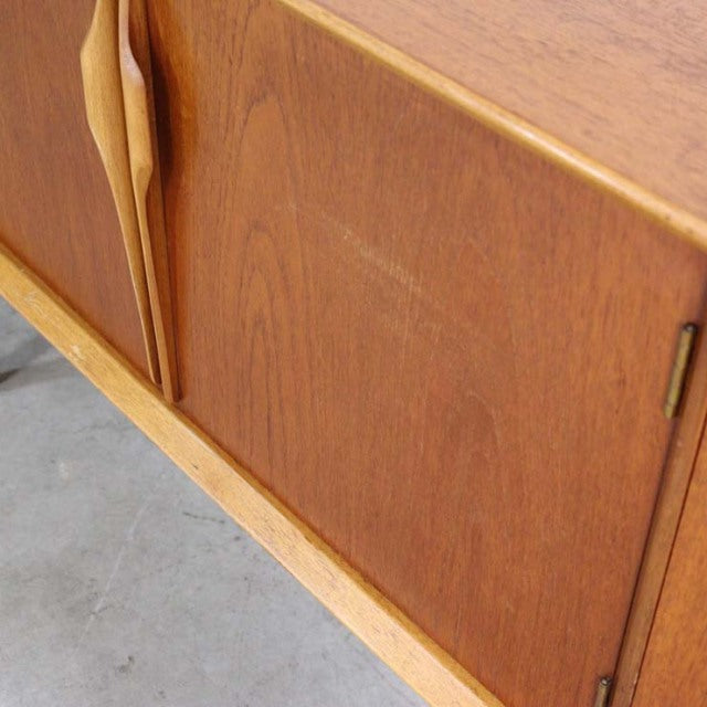 Vintage British mid-century teak sideboard with smooth wood grain and sculpted handles.