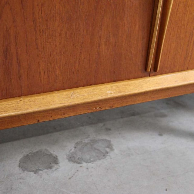 Mid-century British vintage teak sideboard with rich wood grain and slender tapered legs showing aged patina.
