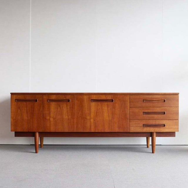 Vintage teak sideboard with rich wood grain, sleek mid-century Danish design, tapered legs, and British craftsmanship.