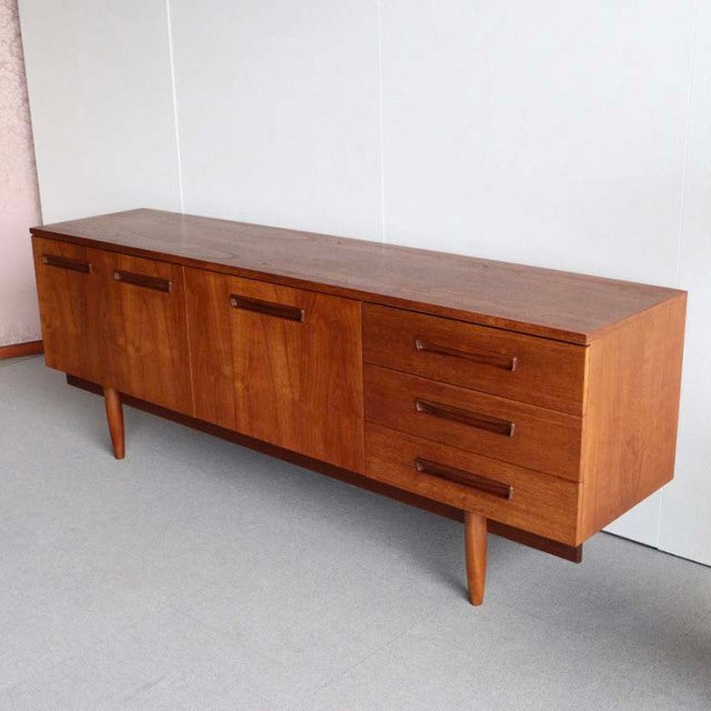 Vintage teak sideboard with mid-century British-Danish design, featuring clean lines, rich wood grain, tapered legs, three.