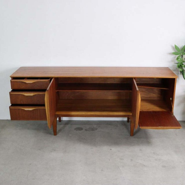 Mid-century British vintage teak sideboard by Jentique with three drawers, open shelving, and drop-down door.