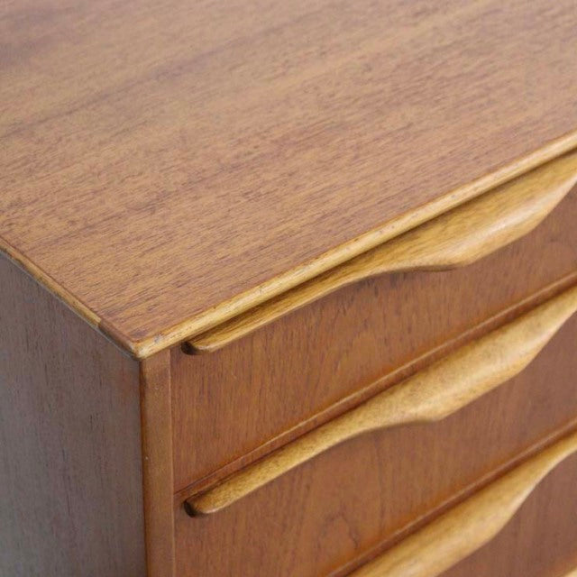 Vintage teak mid-century British sideboard by Jentique with smooth wood grain and sculpted drawer handles.