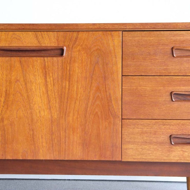 Vintage teak mid-century sideboard with rich wood grain, British design, smooth recessed handles, and tapered legs.