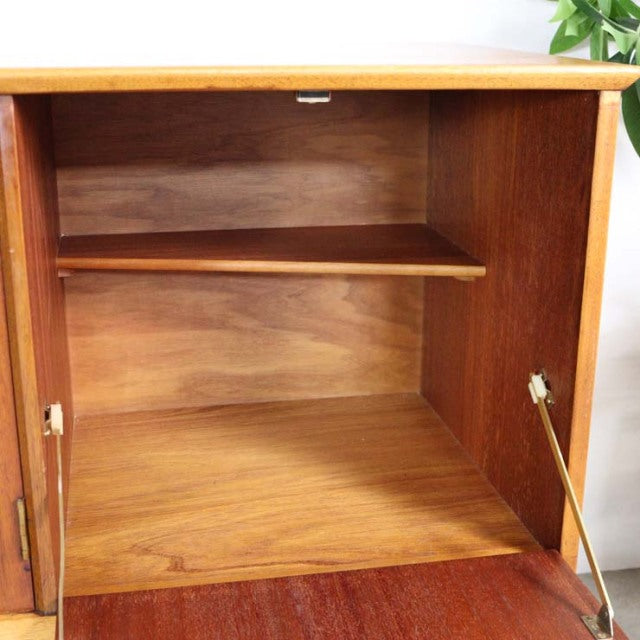 Open teak vintage British mid-century sideboard interior showing smooth wood grain and sturdy shelf with brass door hinges.