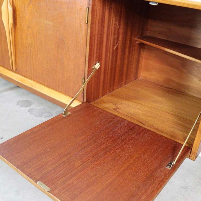 Mid-century British vintage teak sideboard by Jentique with rich wood grain, drop-down door, and brass hinges.