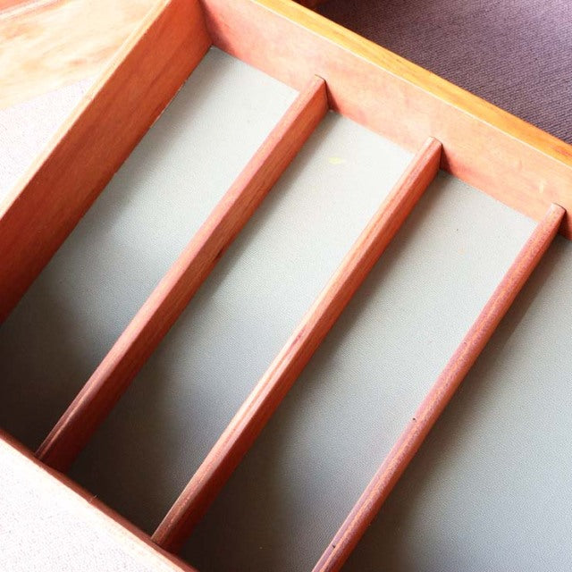Vintage teak wood sideboard drawer interior with smooth dividers and muted green lining, mid-century British-Denmark design.
