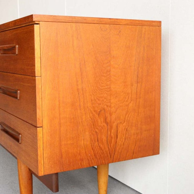 Mid-century vintage teak sideboard with rich wood grain, angled tapered legs, and British-Denmark design influence.