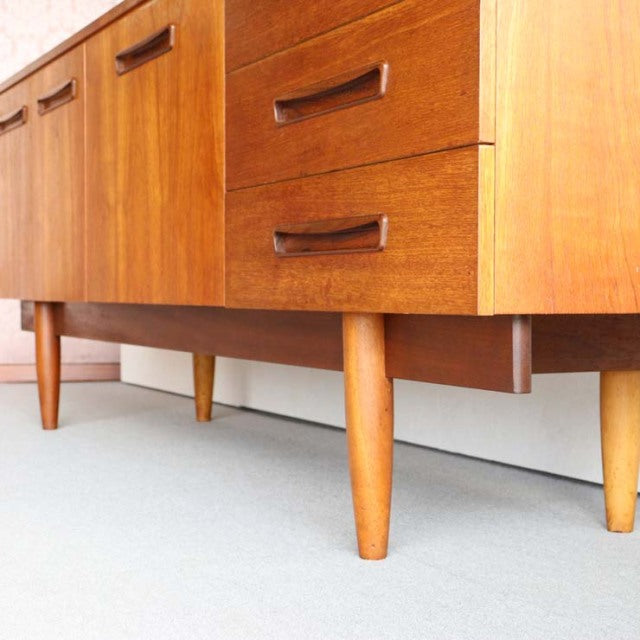 Mid-century vintage teak sideboard with rich wood grain, sleek tapered legs, and British-Denmark design influence.