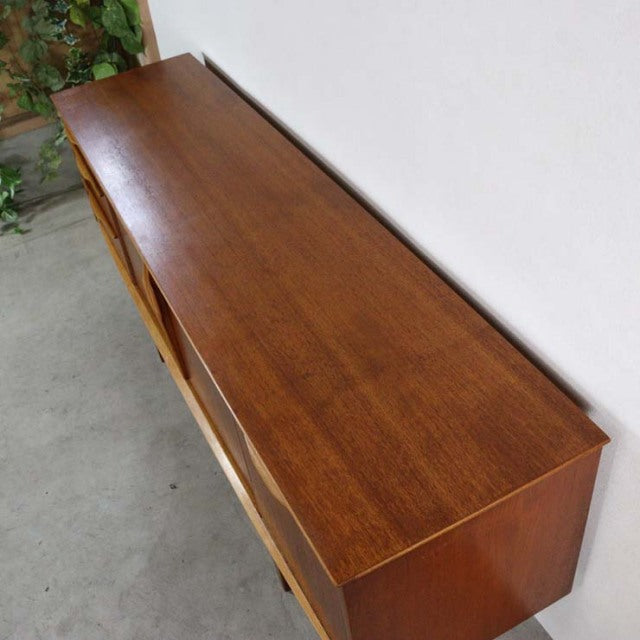 Mid-century British vintage teak Jentique sideboard with sleek wood grain and tapered legs.