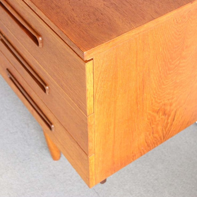 Mid-century British teak sideboard corner with rich wood grain and rounded wooden legs, vintage Denmark design.