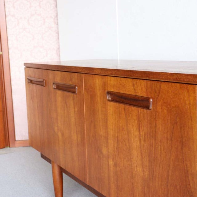 Mid-century vintage teak sideboard with rich wood grain, British-Denmark style, clean lines, and tapered legs.