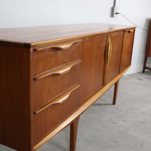 Mid-century British teak sideboard by Jentique with sculpted handles, clean lines, and tapered legs.