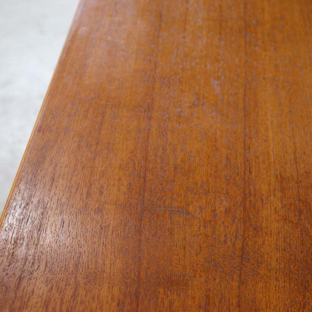 Close-up of vintage teak wood grain on British mid-century Jentique sideboard top, warm reddish-brown finish.