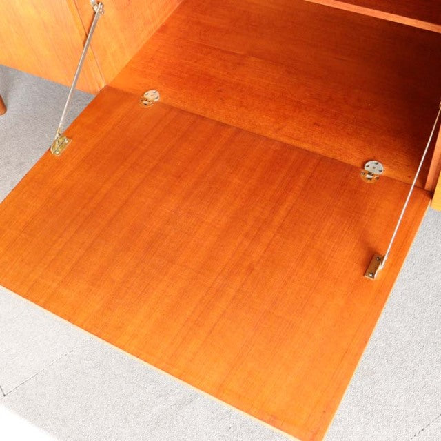 Mid-century vintage teak sideboard door open, smooth wood grain, brass hinges, Danish-British design detail.