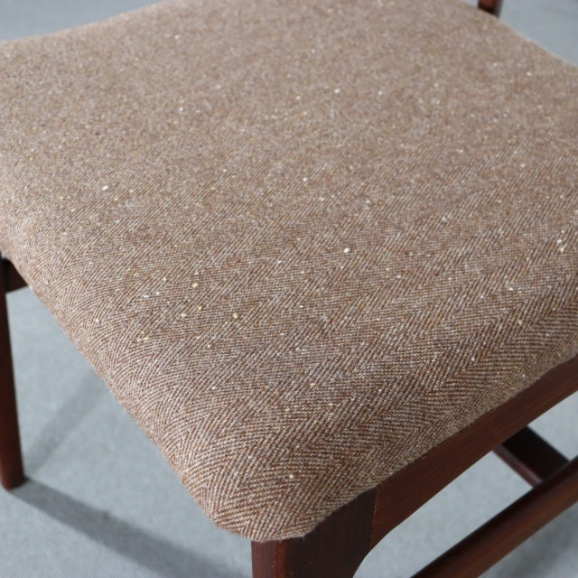 Close-up of mid-century teak dining chair seat upholstered in textured beige fabric with subtle woven pattern and wooden.