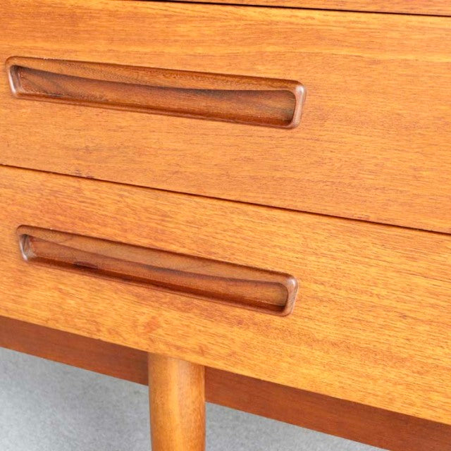 Vintage mid-century teak sideboard drawer front with smooth wood grain and recessed handles, British-Denmark design.