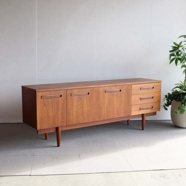 Vintage teak sideboard with rich wood grain, British mid-century design, featuring tapered legs and three drawers on the.
