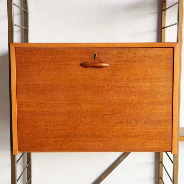 Vintage teak Ladderax shelving unit with drop-front cabinet, mid-century British design, smooth wood grain, and minimalist.