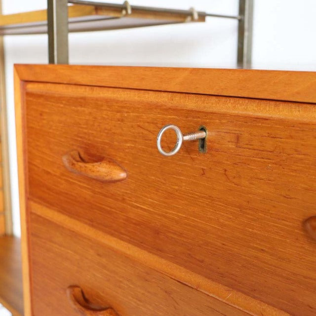 Close-up of vintage teak Ladderax unit shelf drawer with smooth wood grain, curved handles, and key lock, mid-century.