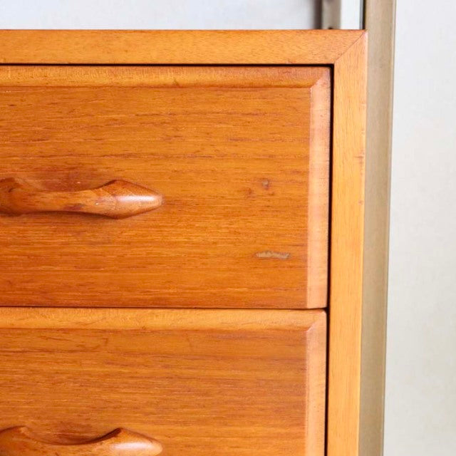 Close-up of vintage British mid-century Ladderax shelving unit's teak drawer front with visible wood grain and sculpted.